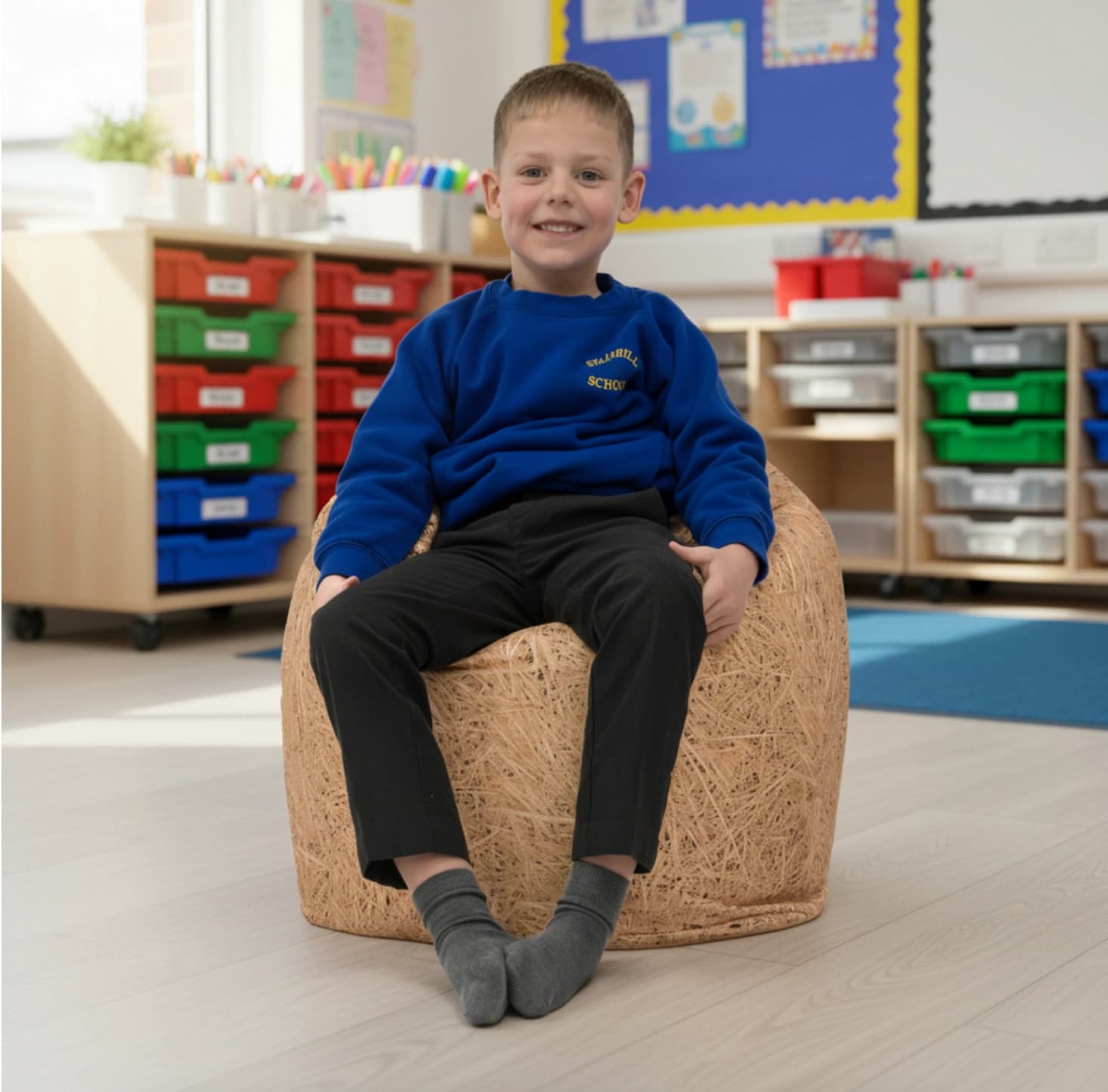 Young boy sitting on a hay nature print bean bag with 100% polyester cover in a classroom.